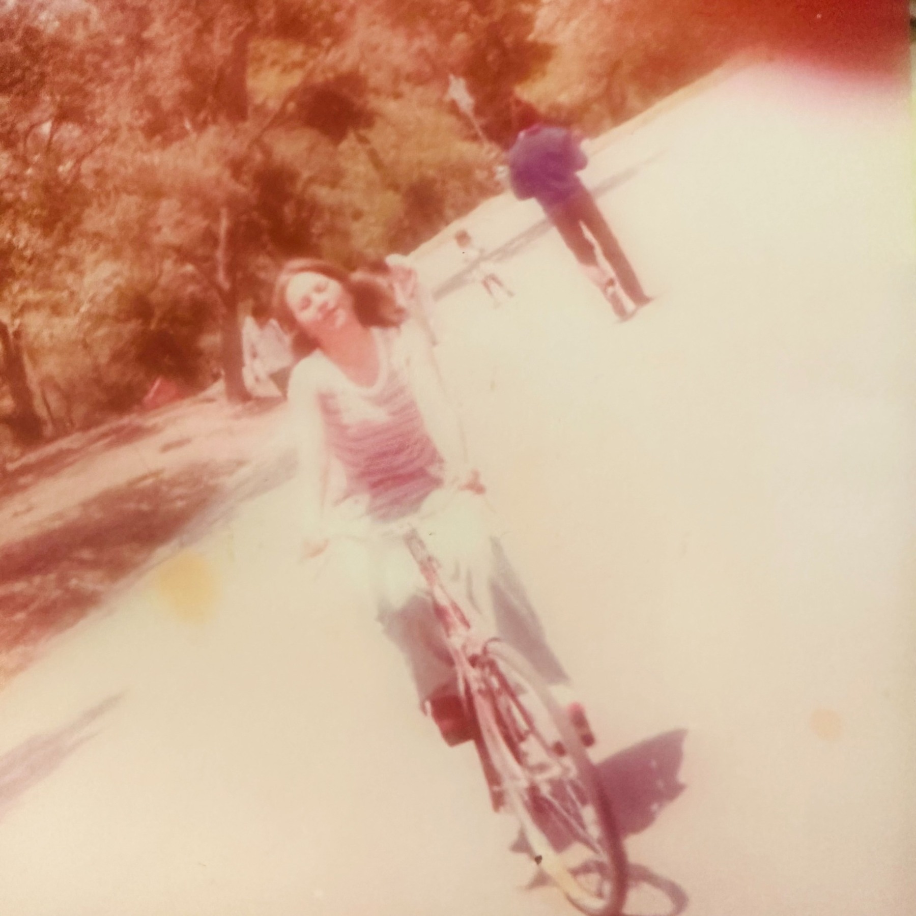 A faded teenage photograph of Rosalia riding a bicycle outdoors